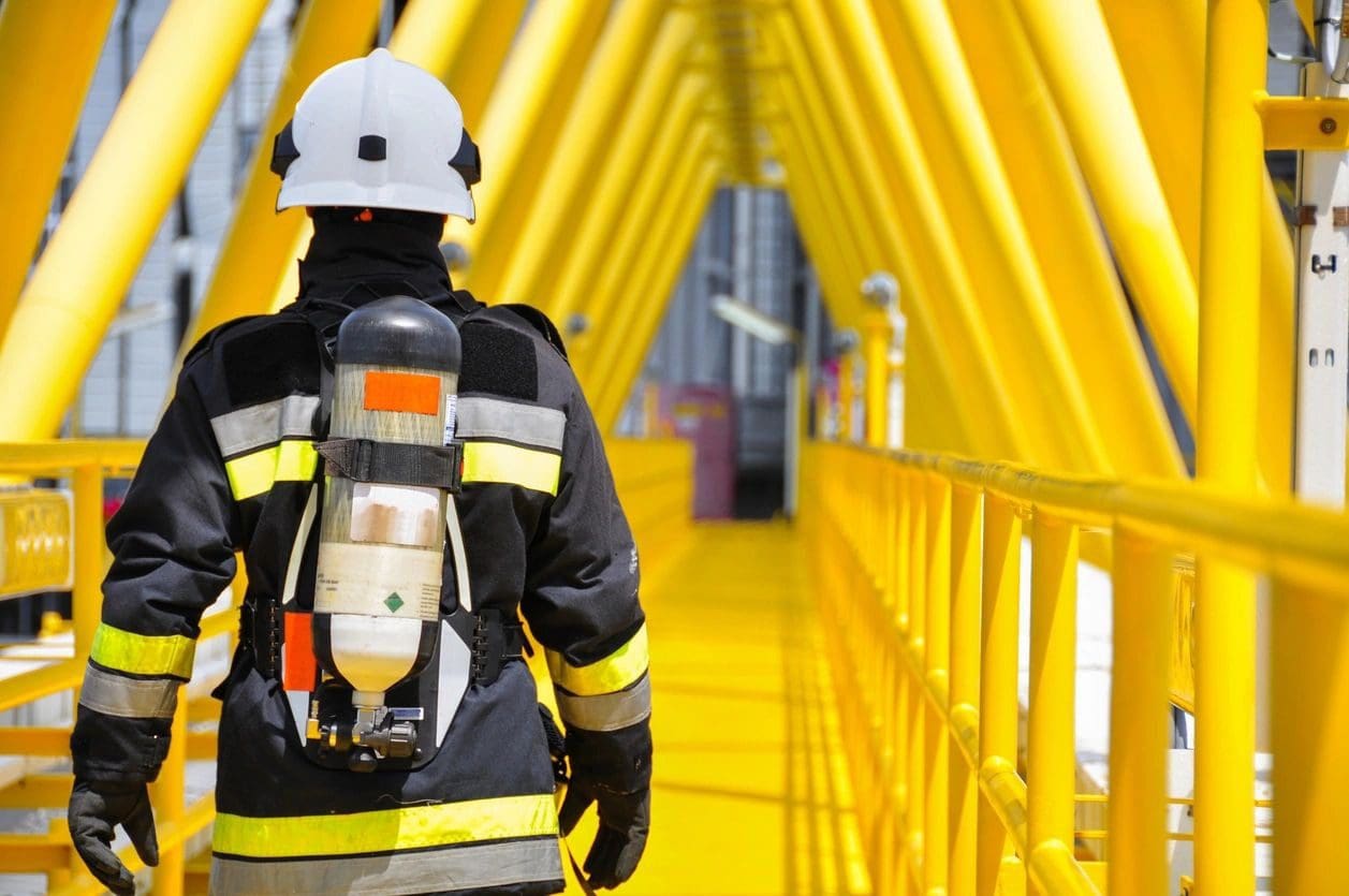 A fireman is walking down the stairs of an oil rig.